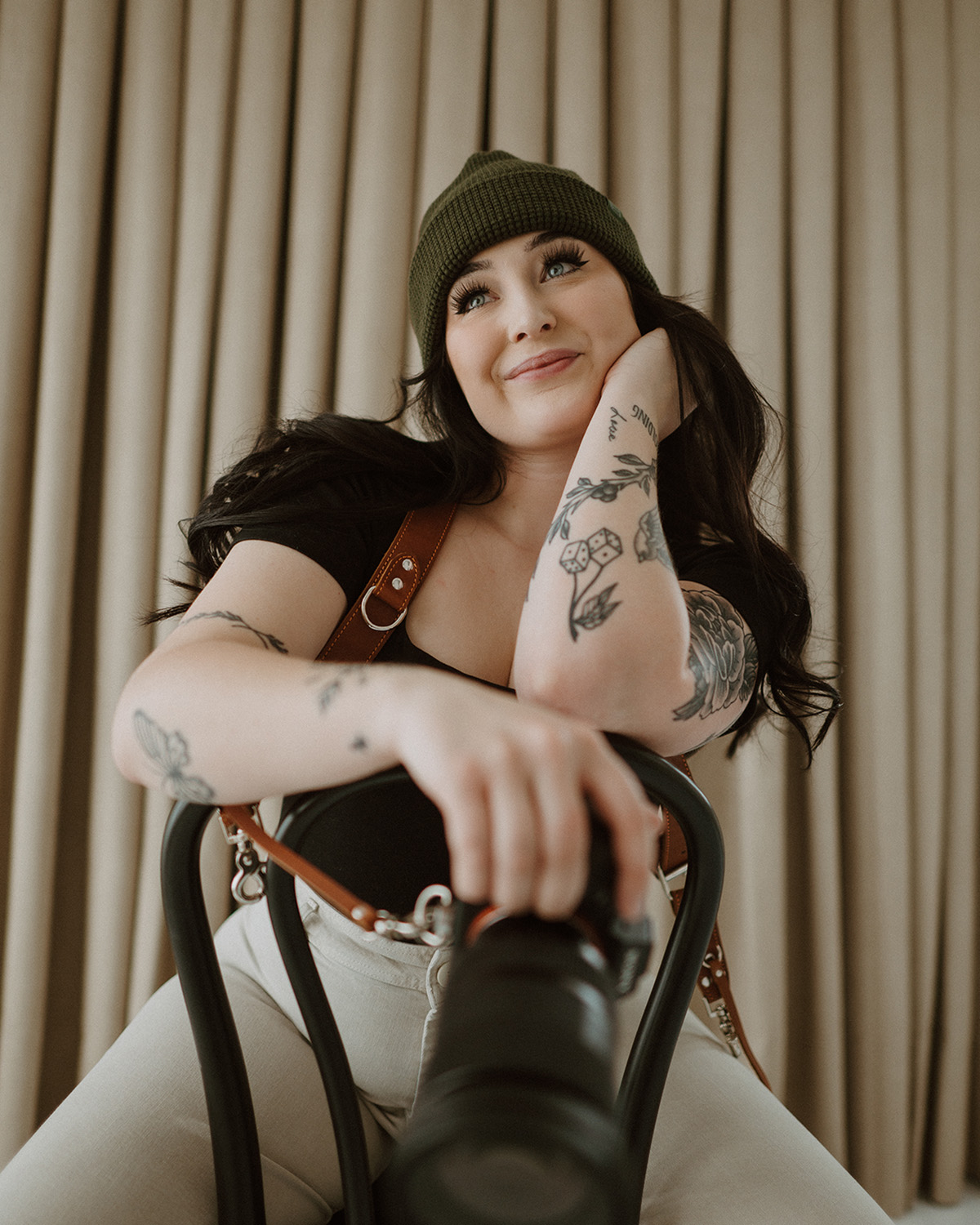 Morgan Furst, Owner of Furst Shot Photography, sits in a chair with her camera in hand